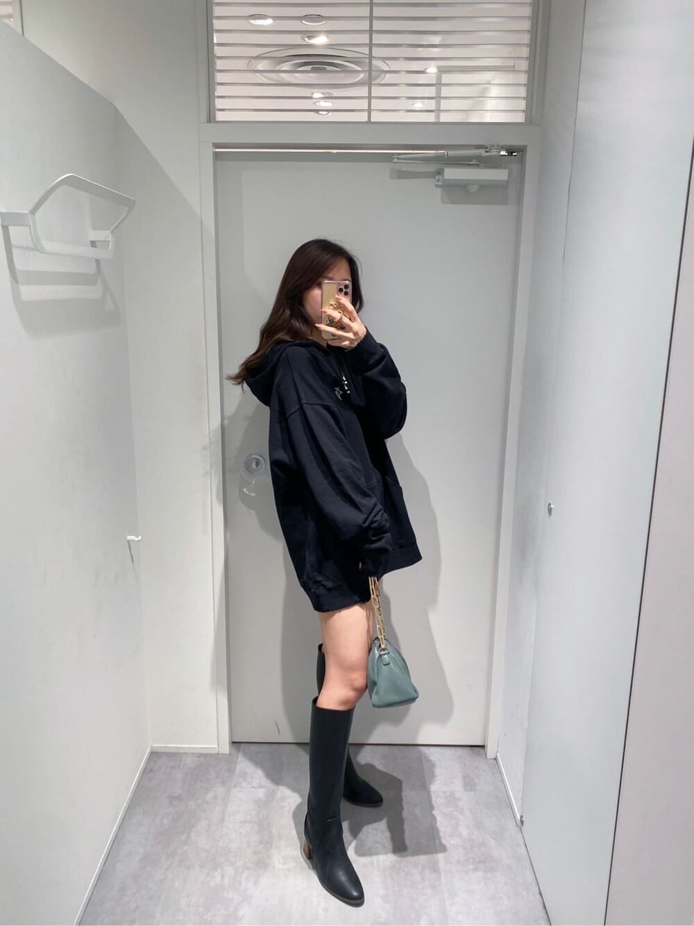 ブラウン系のデニムパンツ、ブラック系のパーカー、グリーン系のショルダーバッグを着用したレディースの秋コーディネートの2枚目の写真