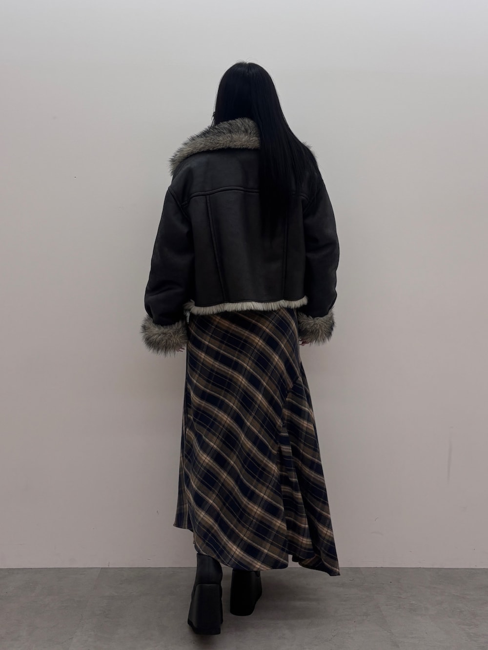 ブラック系のブルゾン、ブラック系のニット/セーター、ブルー系のスカートを着用したレディースの秋コーディネートの3枚目の写真