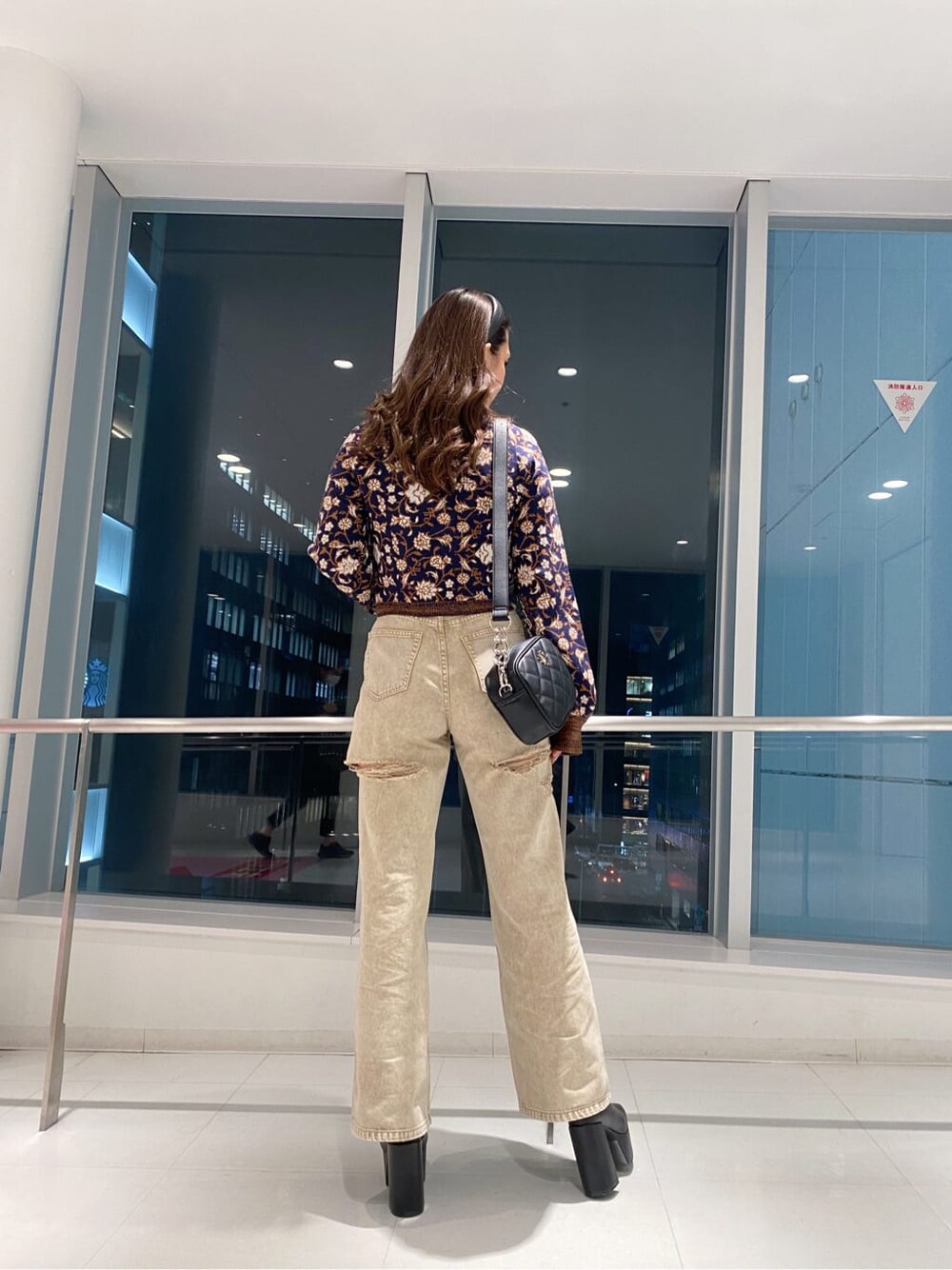 ブラック系のブーツ、ブラック系のショルダーバッグ、ベージュ系のデニムパンツを着用したレディースの秋コーディネートの2枚目の写真