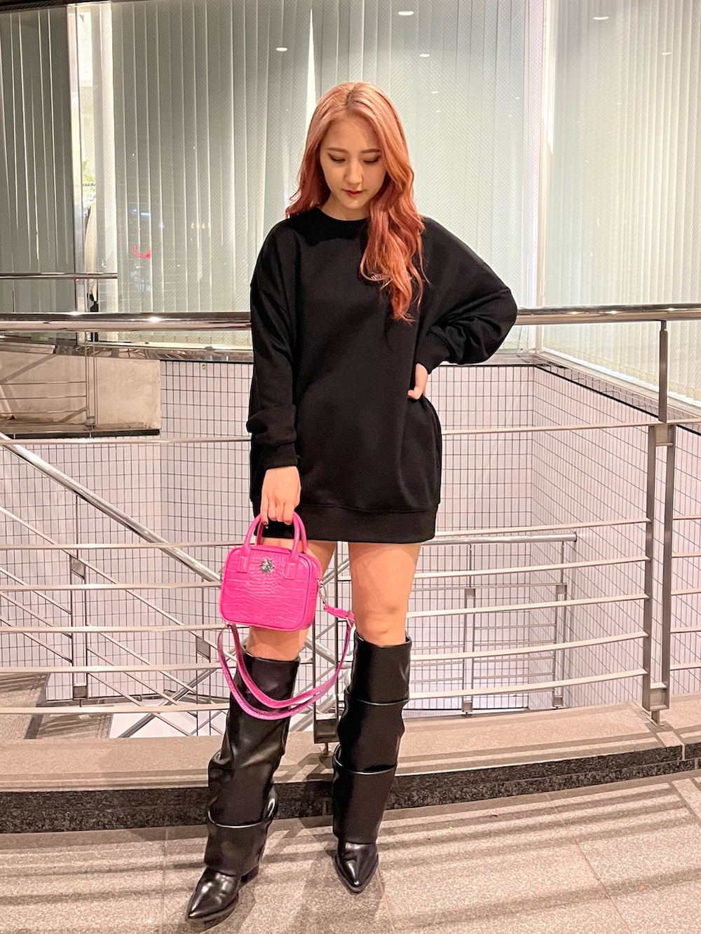 ブラック系のスウェット、ピンク系のショルダーバッグ、ブラック系のブーツを着用したレディースの冬コーディネートの2枚目の写真