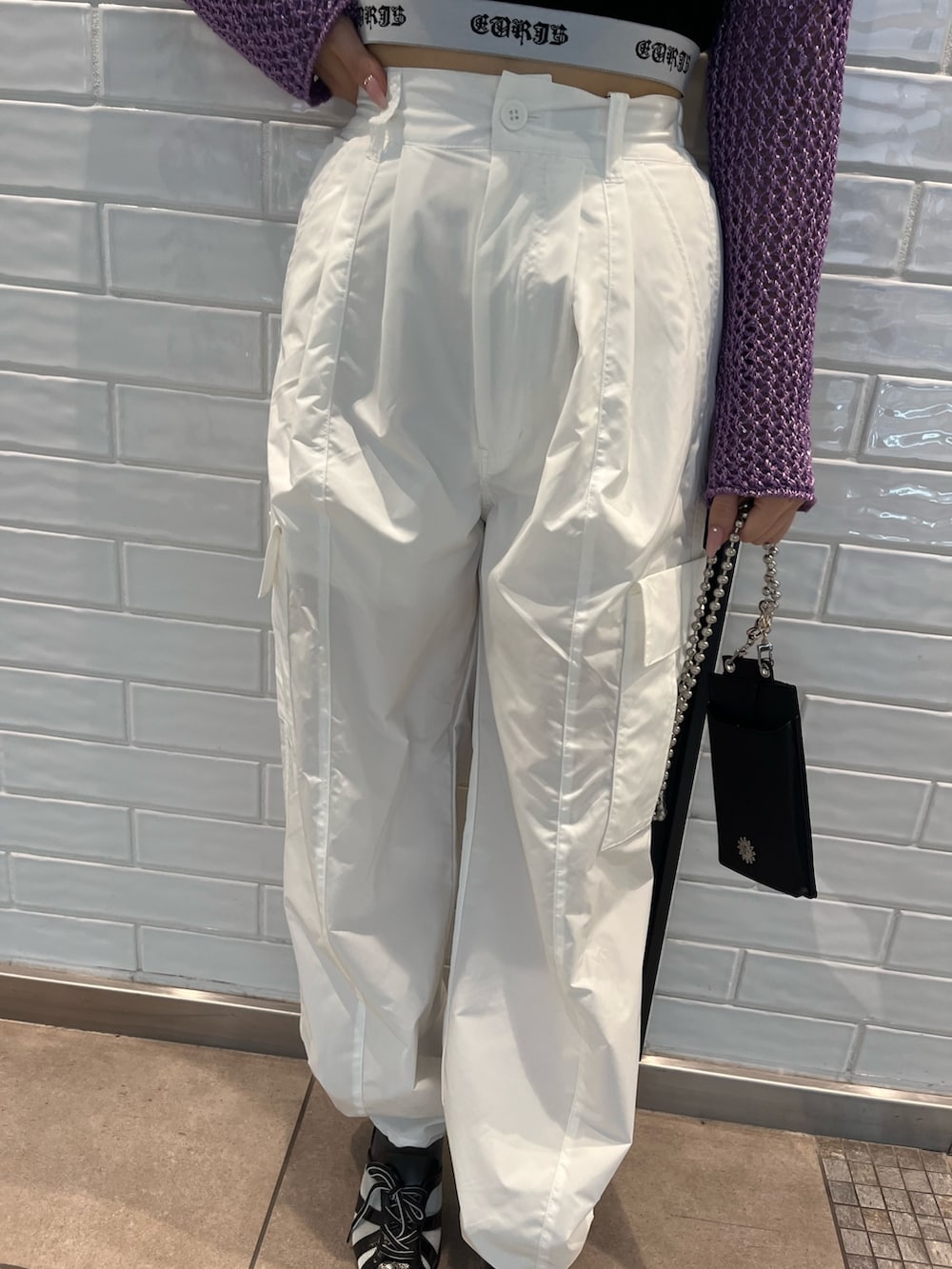 パープル系のニット/セーター、ブラック系のキャミソール、ブラック系のショルダーバッグを着用したレディースの春コーディネートの6枚目の写真