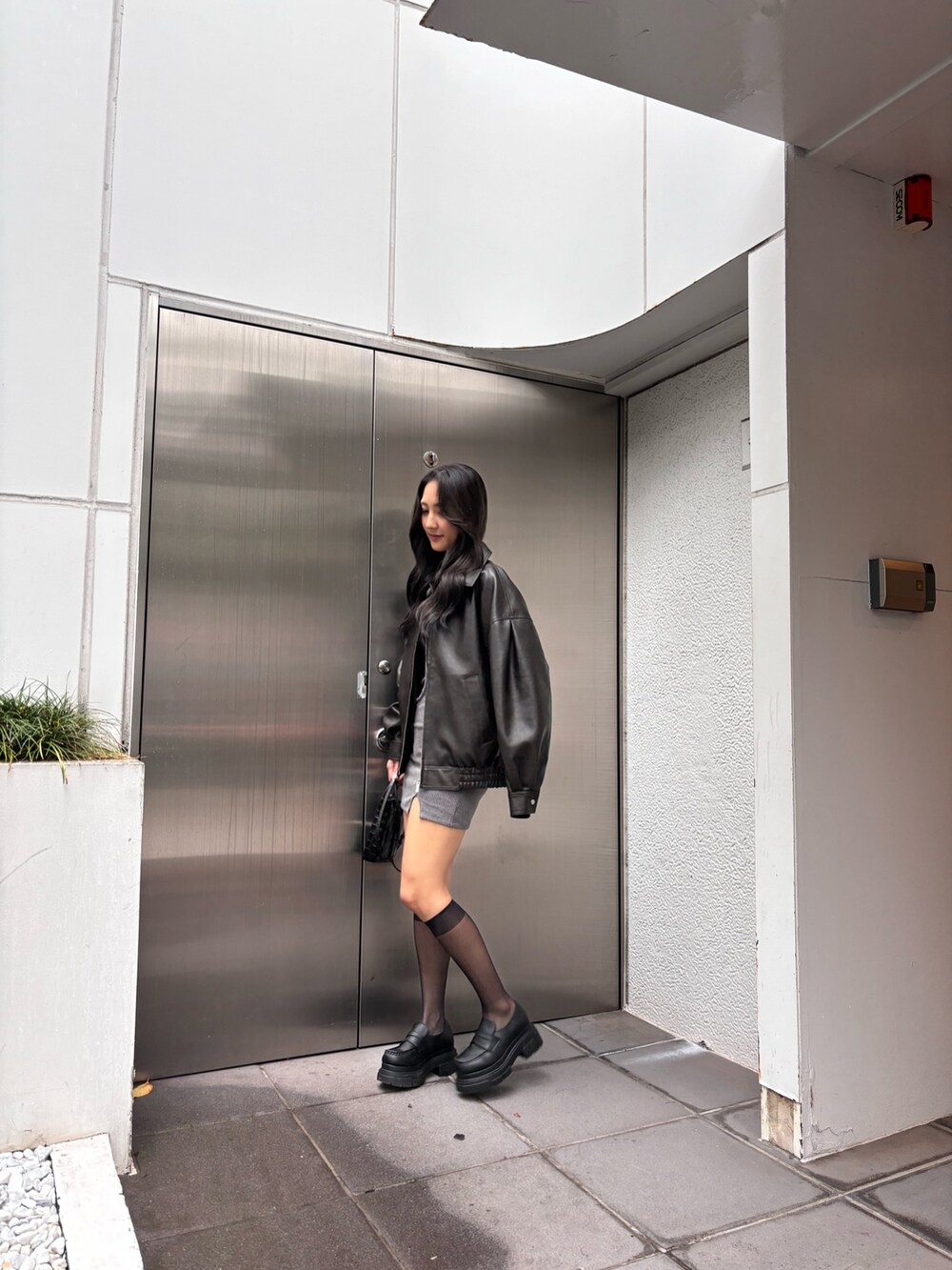 ブラウン系のブルゾン、ブラック系のローファー、グレー系のワンピースを着用したレディースの秋コーディネートの2枚目の写真