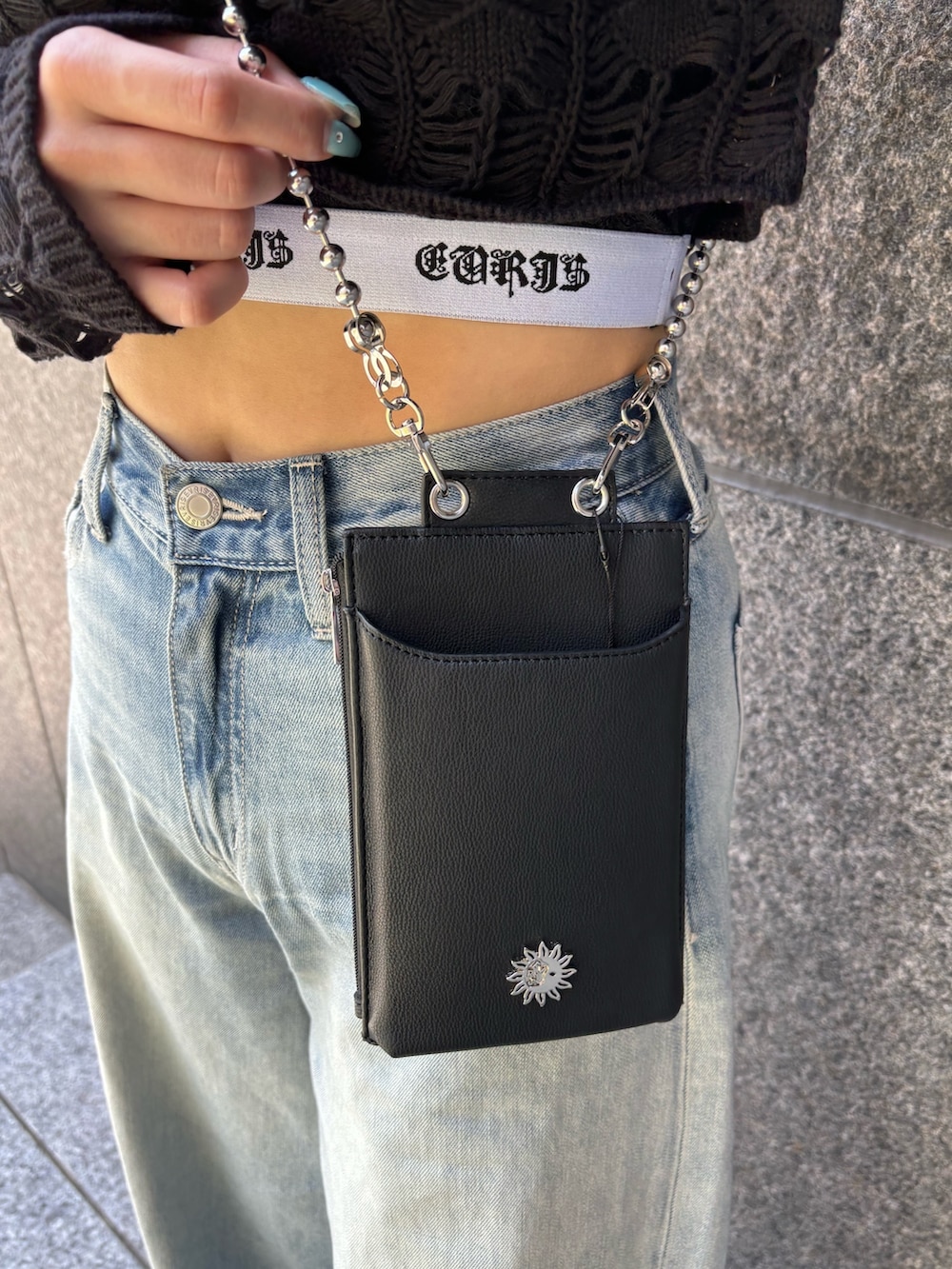 ブラック系のニット/セーター、ブラック系のキャミソール、ブルー系のデニムパンツを着用したレディースの春コーディネートの6枚目の写真