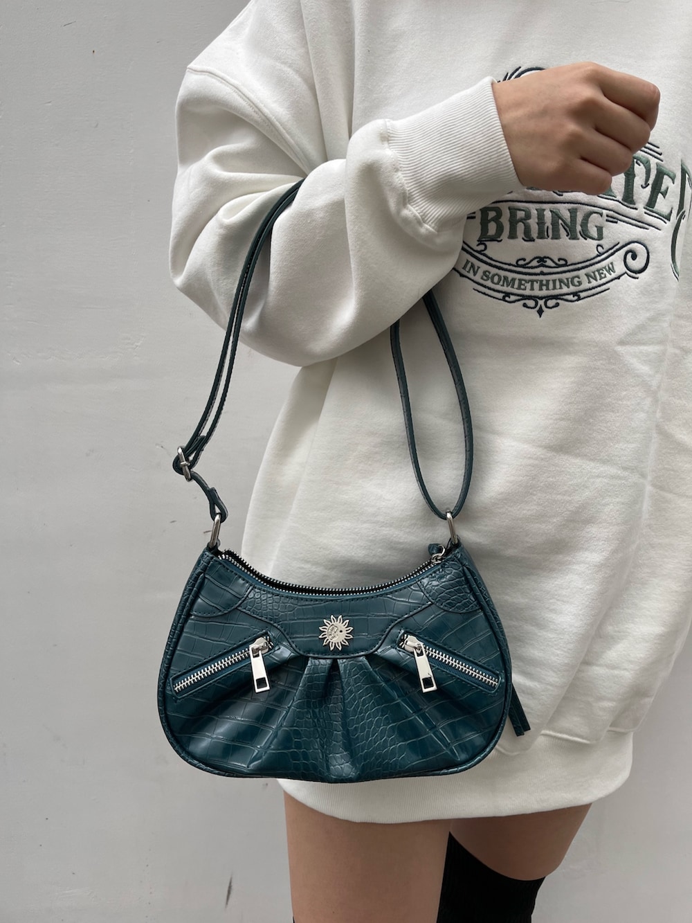 ホワイト系のスウェット、ブルー系のショルダーバッグ、ブラック系のブーツを着用したレディースの秋コーディネートの4枚目の写真