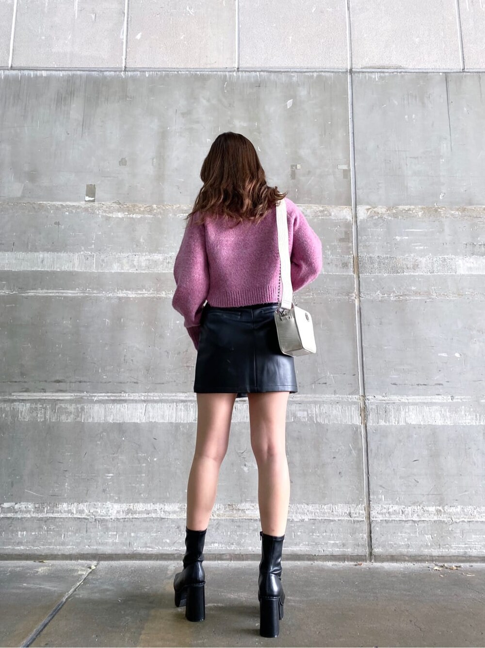 ブラック系のブーツ、ピンク系のニット/セーター、ホワイト系のショルダーバッグを着用したレディースの秋コーディネートの2枚目の写真