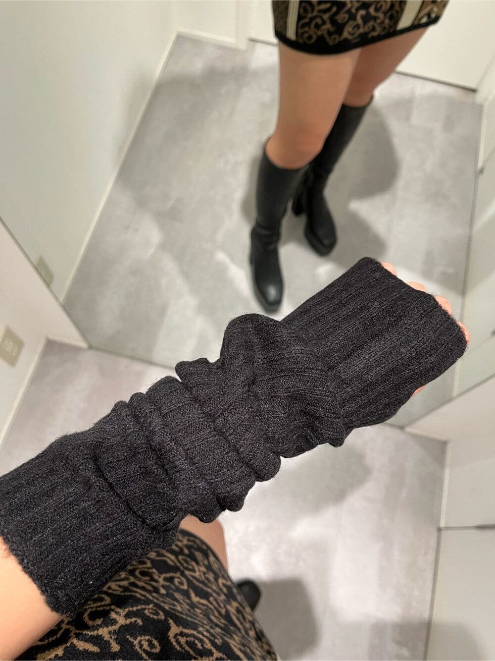 ブラック系のスカート、ブラック系のブーツ、ブラック系のニット/セーターを着用したレディースの秋コーディネートの4枚目の写真