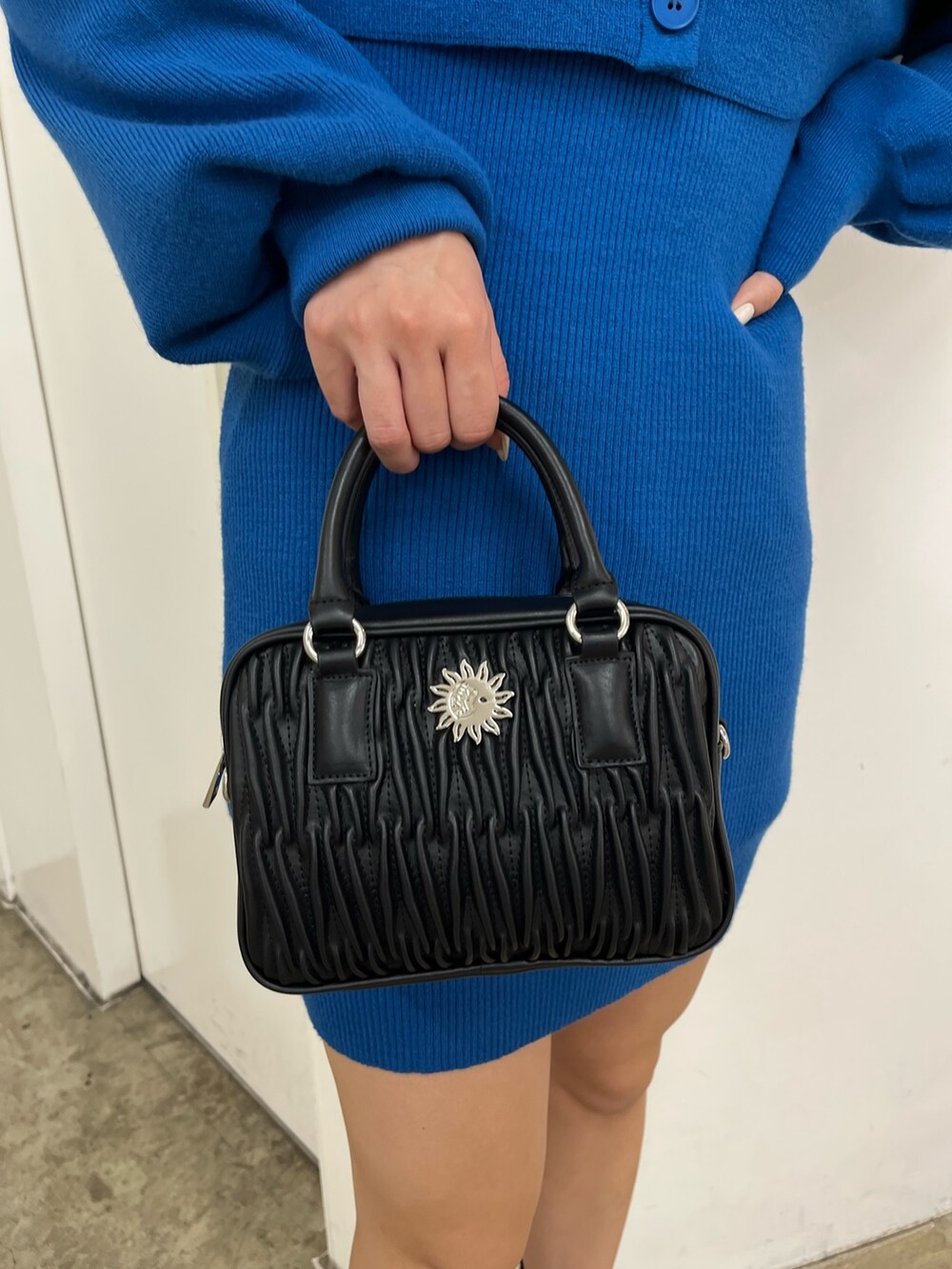 ブラック系のショルダーバッグ、ブルー系のワンピース、ホワイト系のブーツを着用したレディースの秋コーディネートの6枚目の写真