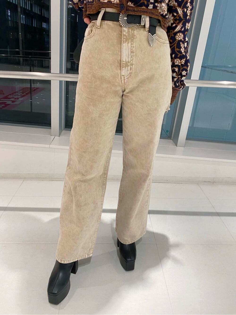 ブラック系のブーツ、ブラック系のショルダーバッグ、ベージュ系のデニムパンツを着用したレディースの秋コーディネートの4枚目の写真