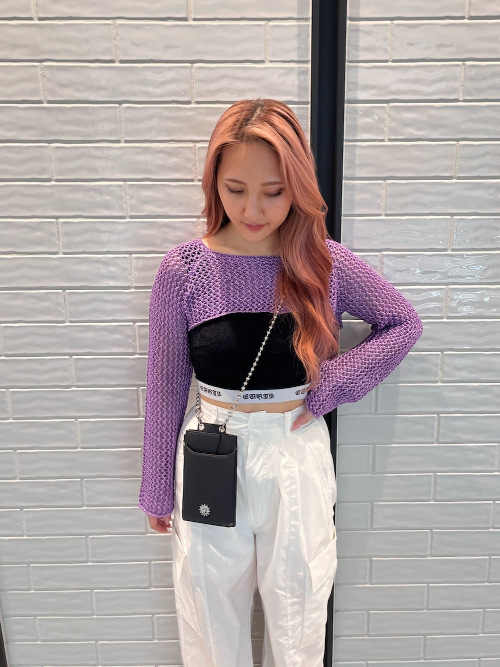 パープル系のニット/セーター、ブラック系のキャミソール、ブラック系のショルダーバッグを着用したレディースの春コーディネートの3枚目の写真