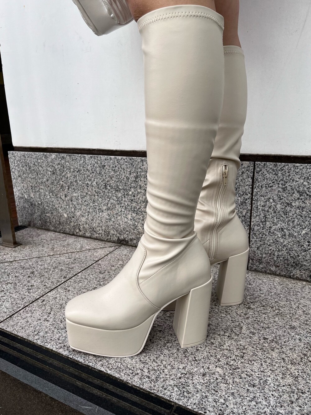 グレー系のニット/セーター、ホワイト系のショルダーバッグ、ホワイト系のブーツを着用したレディースの秋コーディネートの6枚目の写真