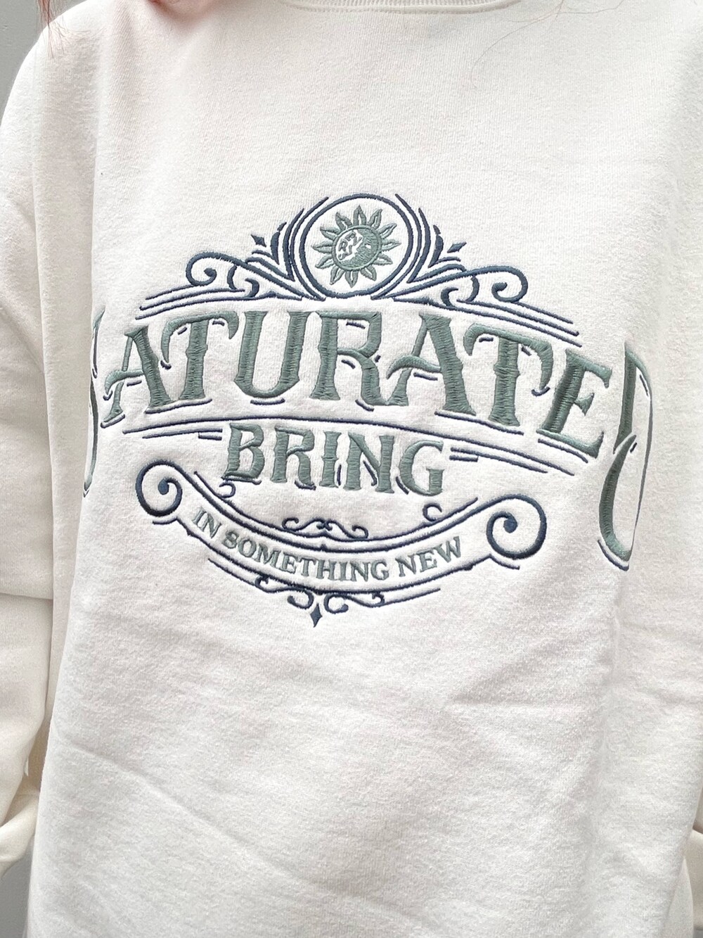 ホワイト系のスウェット、ブルー系のショルダーバッグ、ブラック系のブーツを着用したレディースの秋コーディネートの3枚目の写真