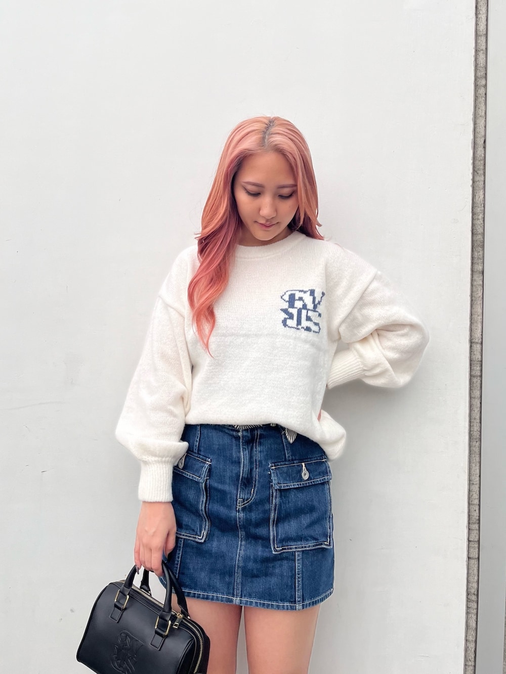 ホワイト系のニット/セーター、ブルー系のデニムスカート、ブラック系のボストンバッグを着用したレディースの冬コーディネートの3枚目の写真