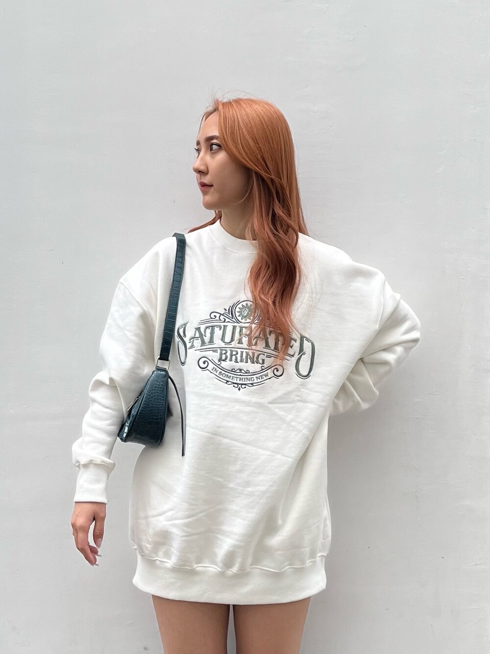 ホワイト系のスウェット、ブルー系のショルダーバッグ、ブラック系のブーツを着用したレディースの秋コーディネートの2枚目の写真