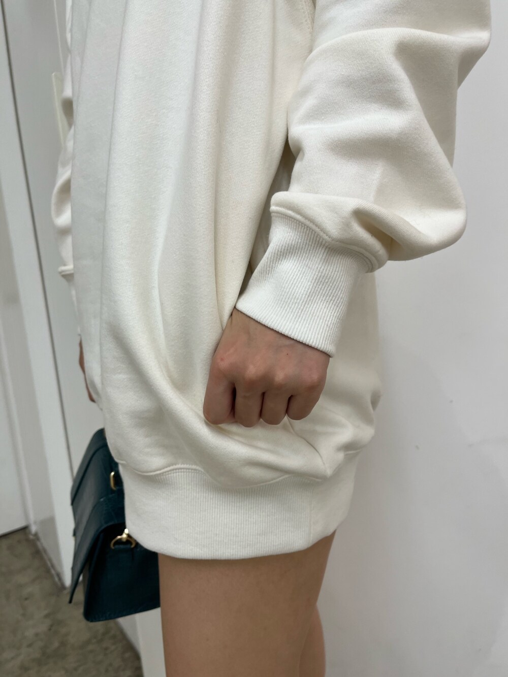 ホワイト系のスウェット、ブラック系のデニムスカート、ブラック系のブーツを着用したレディースの秋コーディネートの6枚目の写真