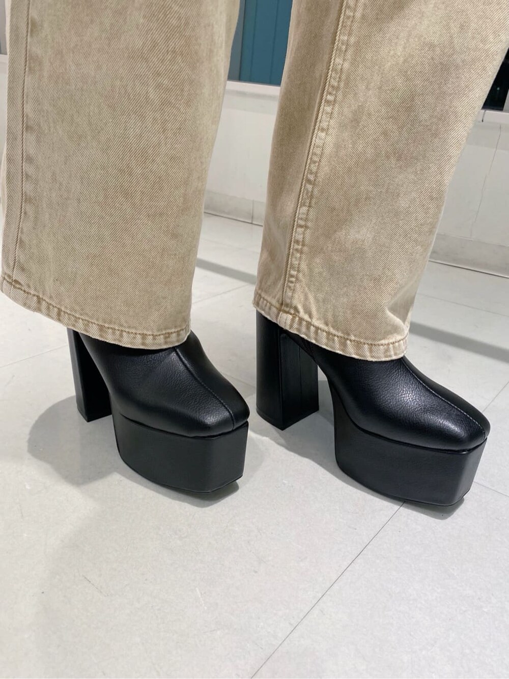 ブラック系のブーツ、ブラック系のショルダーバッグ、ベージュ系のデニムパンツを着用したレディースの秋コーディネートの5枚目の写真