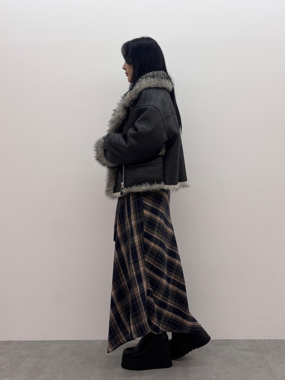 ブラック系のブルゾン、ブラック系のニット/セーター、ブルー系のスカートを着用したレディースの秋コーディネートの2枚目の写真