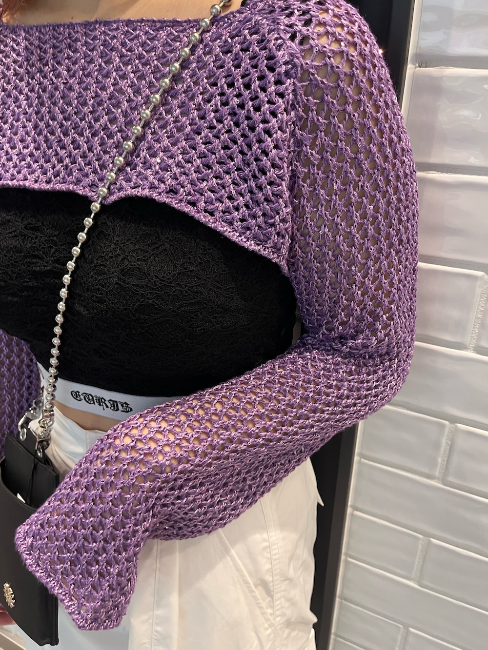 パープル系のニット/セーター、ブラック系のキャミソール、ブラック系のショルダーバッグを着用したレディースの春コーディネートの4枚目の写真