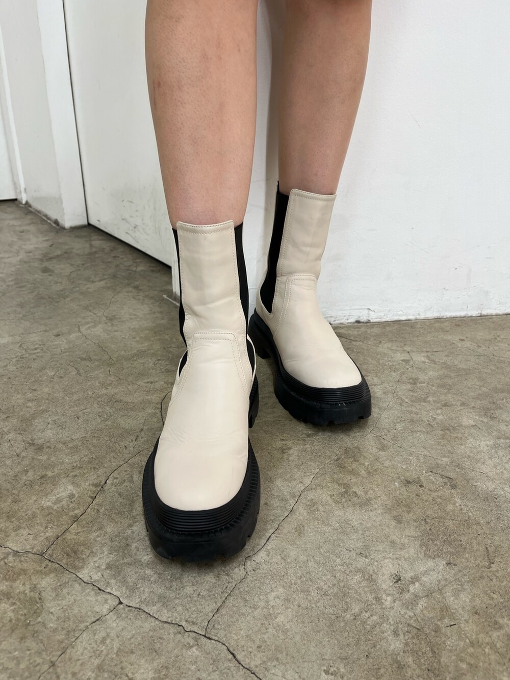 ブラック系のショルダーバッグ、ブルー系のワンピース、ホワイト系のブーツを着用したレディースの秋コーディネートの7枚目の写真