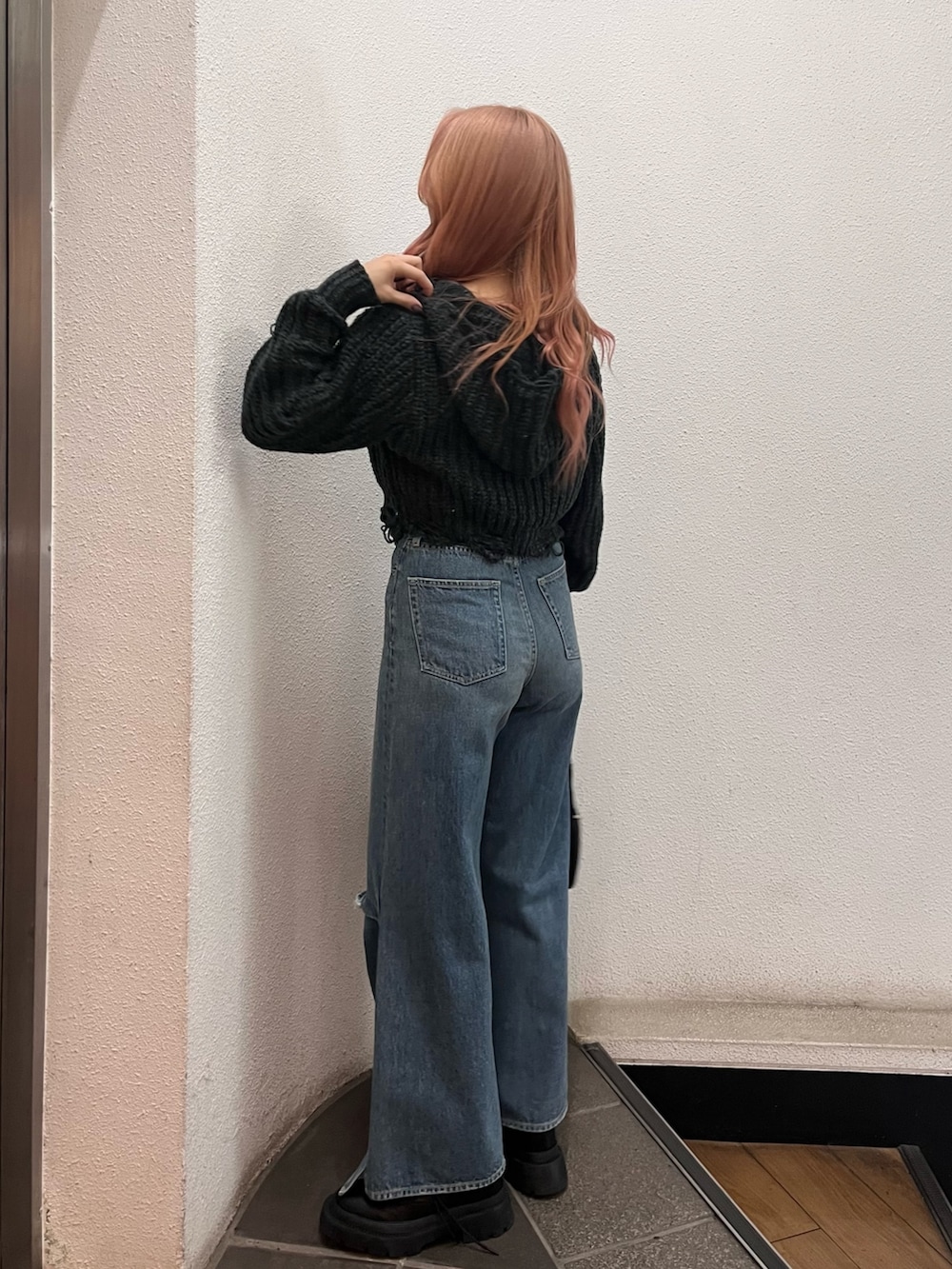 ブルー系のデニムパンツ、ブラック系のハンドバッグ、ブラック系のブーツを着用したレディースの冬コーディネートの3枚目の写真