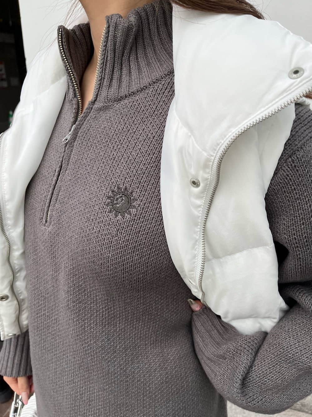 グレー系のニット/セーター、ホワイト系のショルダーバッグ、ホワイト系のブーツを着用したレディースの秋コーディネートの4枚目の写真