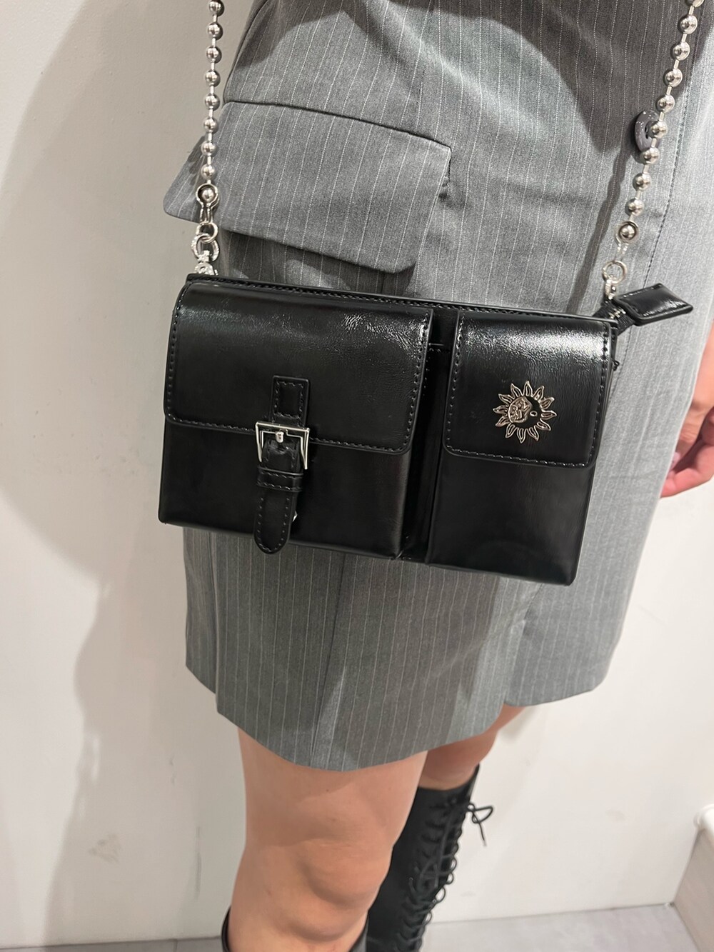 グレー系のワンピース、ブラック系のブーツ、ブラック系のショルダーバッグを着用したレディースの夏コーディネートの3枚目の写真