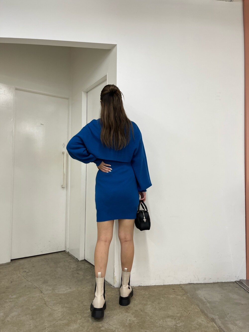 ブラック系のショルダーバッグ、ブルー系のワンピース、ホワイト系のブーツを着用したレディースの秋コーディネートの2枚目の写真