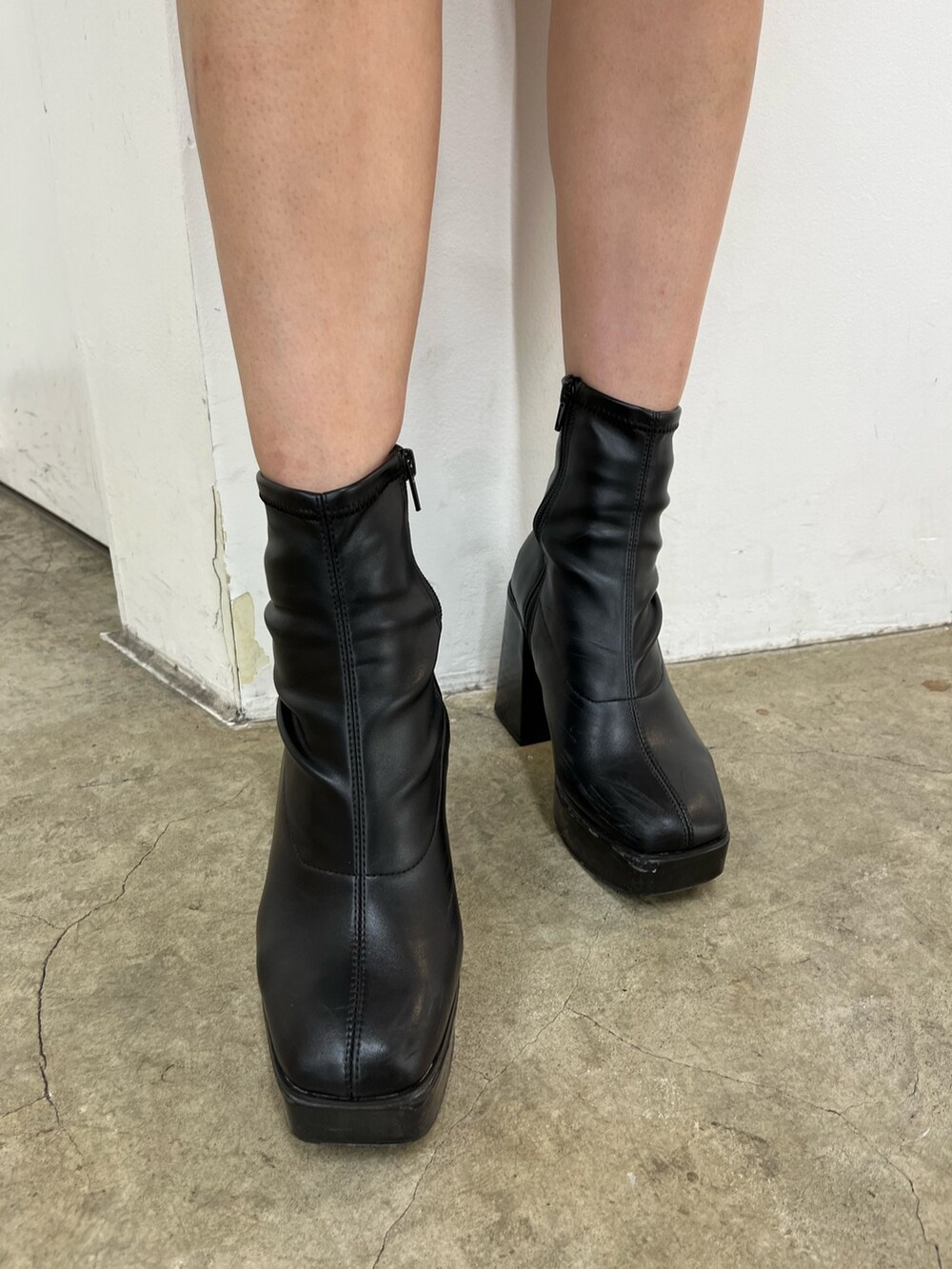 ホワイト系のスウェット、ブラック系のデニムスカート、ブラック系のブーツを着用したレディースの秋コーディネートの8枚目の写真