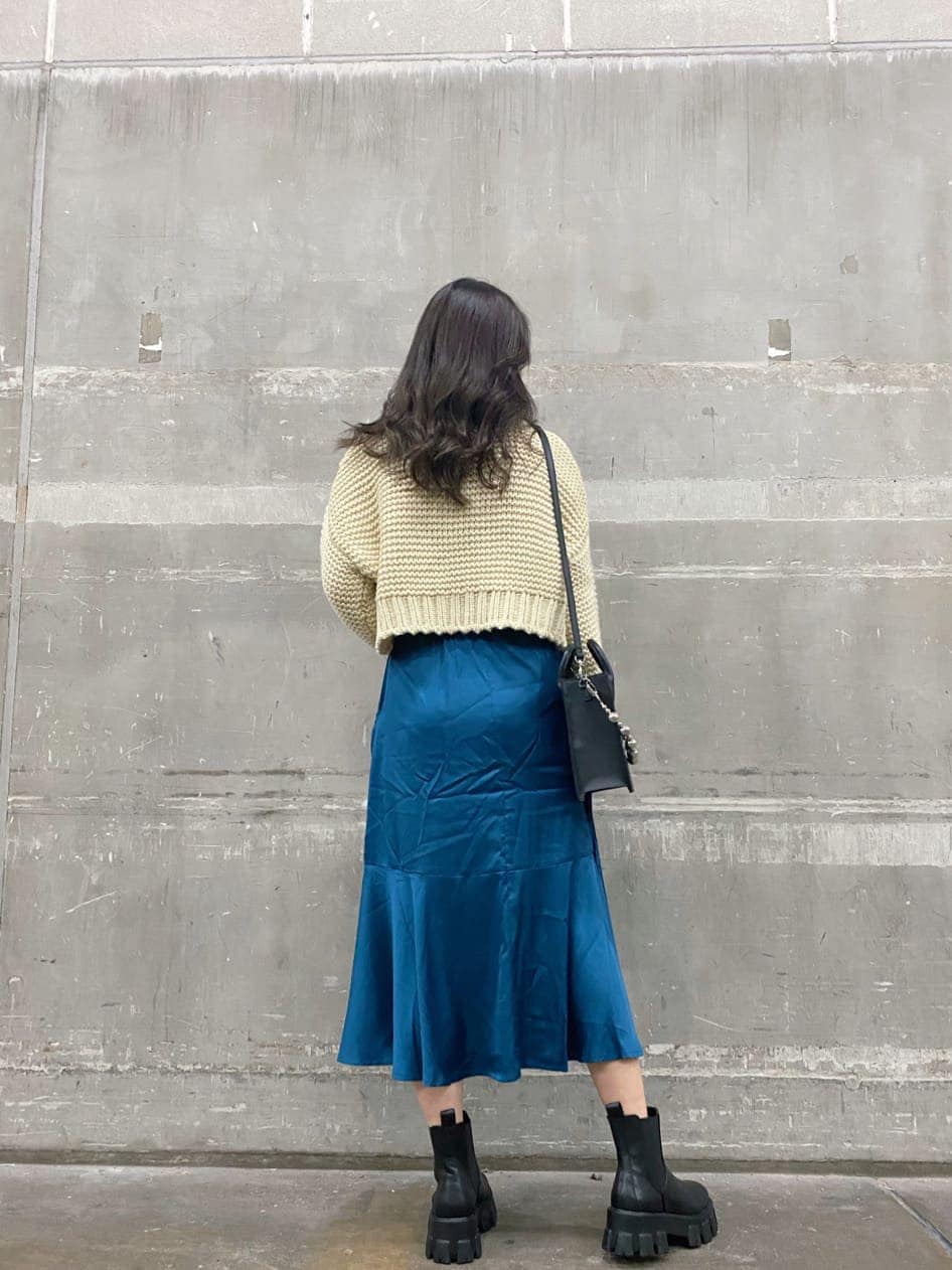 ホワイト系のニット/セーター、ブラック系のブーツ、ブルー系のスカートを着用したレディースの秋コーディネートの2枚目の写真