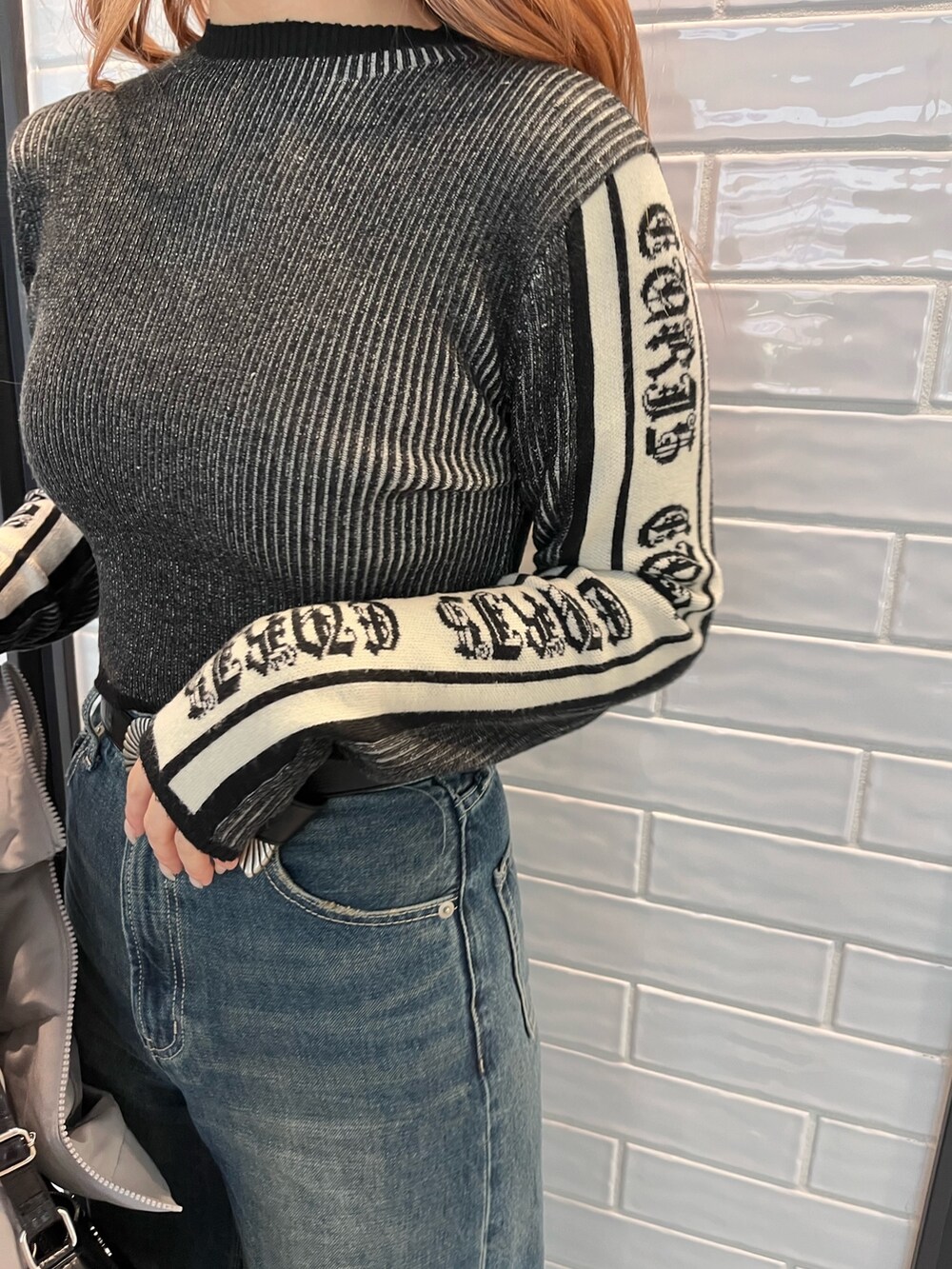 グレー系のダウンジャケット/コート、ブラック系のニット/セーター、ブルー系のデニムパンツを着用したレディースの冬コーディネートの5枚目の写真