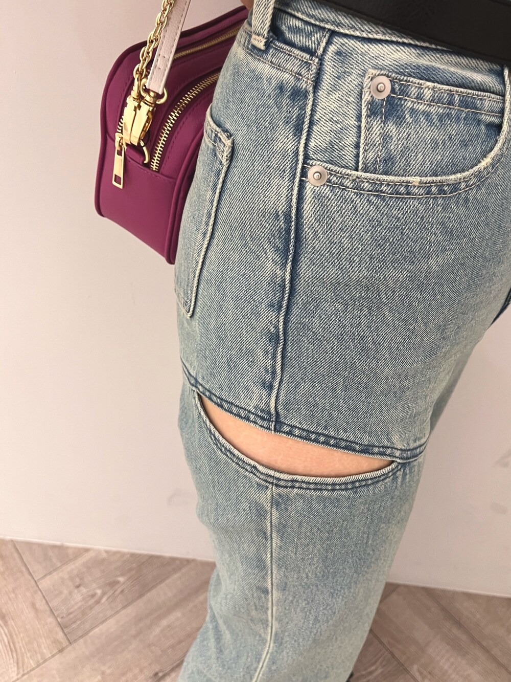 ブルー系のデニムパンツ、ブラック系のニット/セーター、パープル系のショルダーバッグを着用したレディースの春コーディネートの6枚目の写真