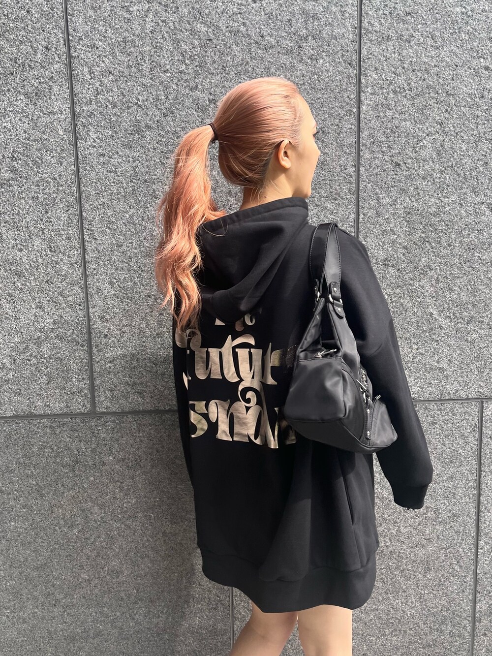 ブラック系のパーカー、ブラック系のハンドバッグ、シルバー系のブーツを着用したレディースの冬コーディネートの3枚目の写真