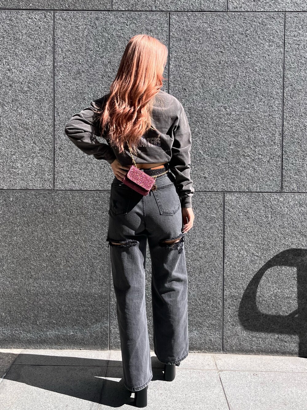 グレー系のTシャツ/カットソー、ブラック系のデニムパンツ、ピンク系のショルダーバッグを着用したレディースの冬コーディネートの2枚目の写真