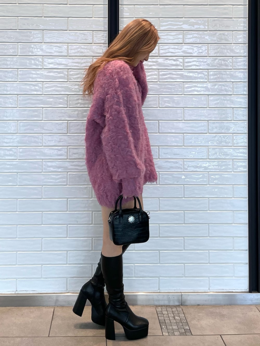 ピンク系のカーディガン/ボレロ、ブラック系のショルダーバッグ、ブラック系のブーツを着用したレディースの冬コーディネートの2枚目の写真