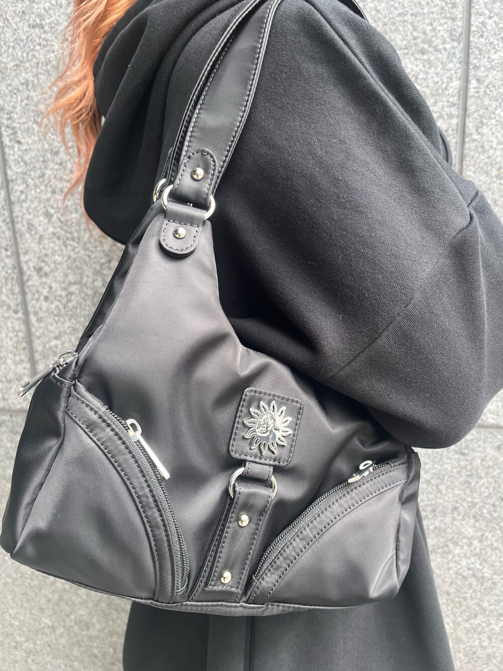 ブラック系のパーカー、ブラック系のハンドバッグ、シルバー系のブーツを着用したレディースの冬コーディネートの6枚目の写真