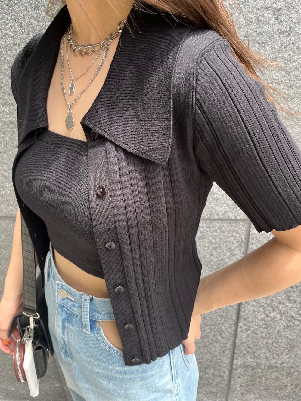 ブラック系のショルダーバッグ、ブルー系のデニムパンツ、ブラック系のニット/セーターを着用したレディースの夏コーディネートの5枚目の写真