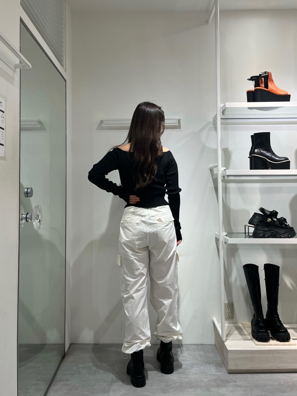 ブラック系のニット/セーター、ブラック系のブーツ、ホワイト系のカーゴパンツを着用したレディースの春コーディネートの2枚目の写真