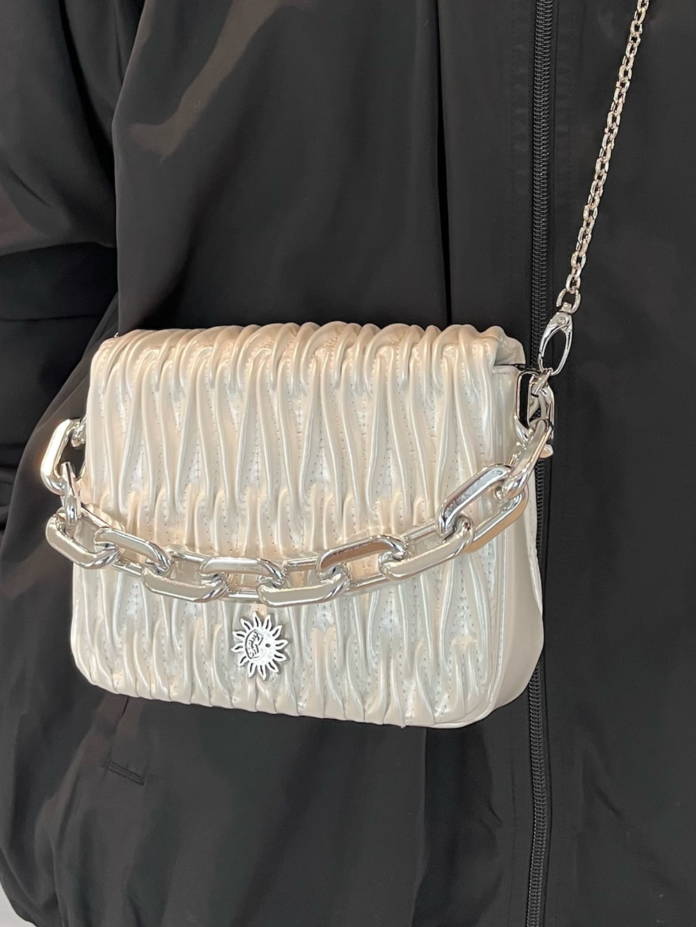 ブラック系のブーツ、ブラック系のナイロンジャケット、ホワイト系のショルダーバッグを着用したレディースの秋コーディネートの3枚目の写真