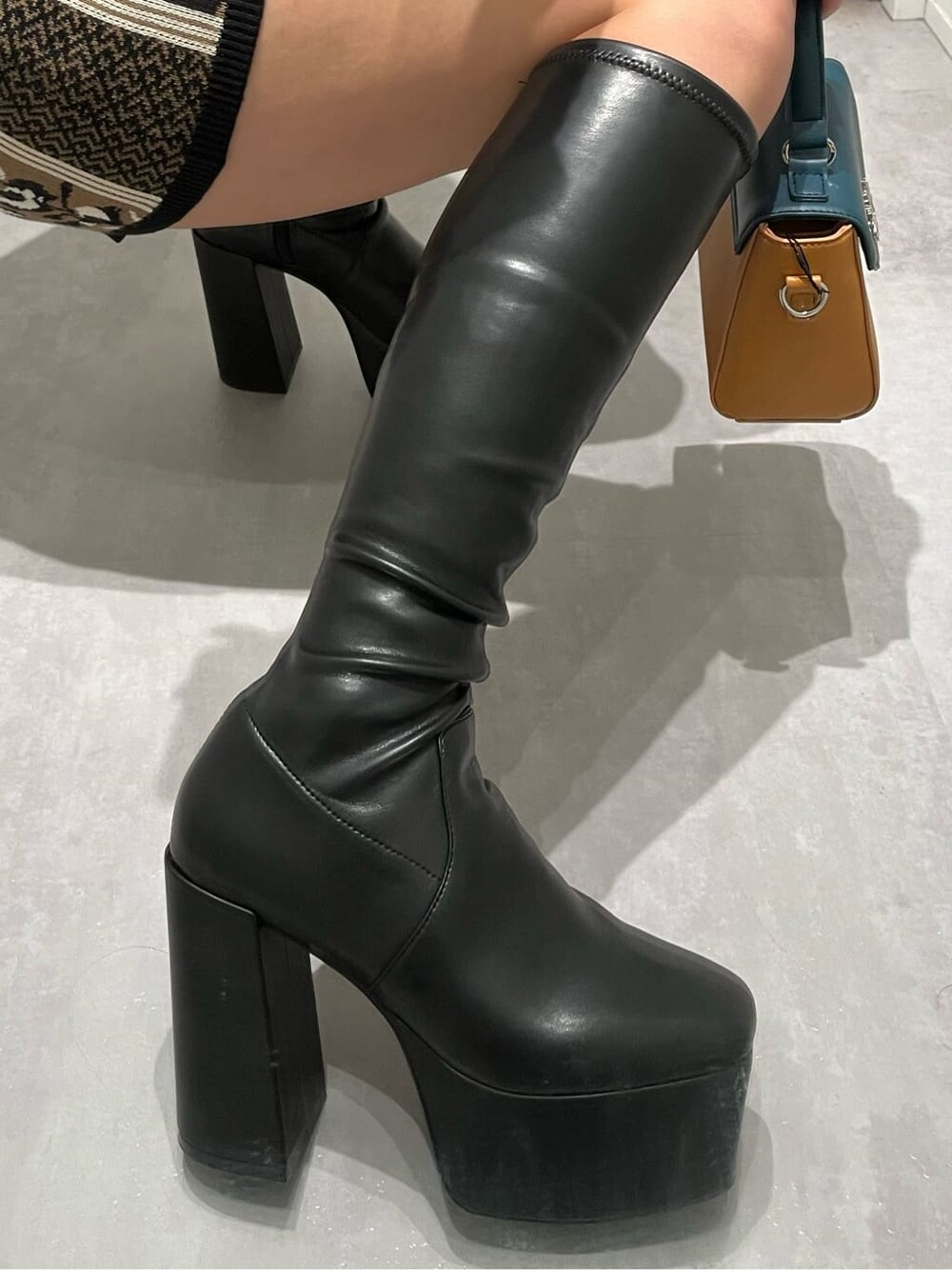 ブラック系のスカート、ブラック系のブーツ、ブラック系のニット/セーターを着用したレディースの秋コーディネートの6枚目の写真