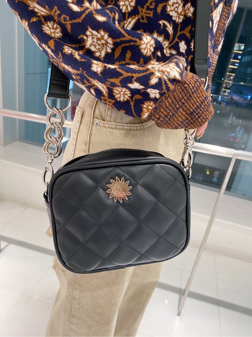 ブラック系のブーツ、ブラック系のショルダーバッグ、ベージュ系のデニムパンツを着用したレディースの秋コーディネートの6枚目の写真