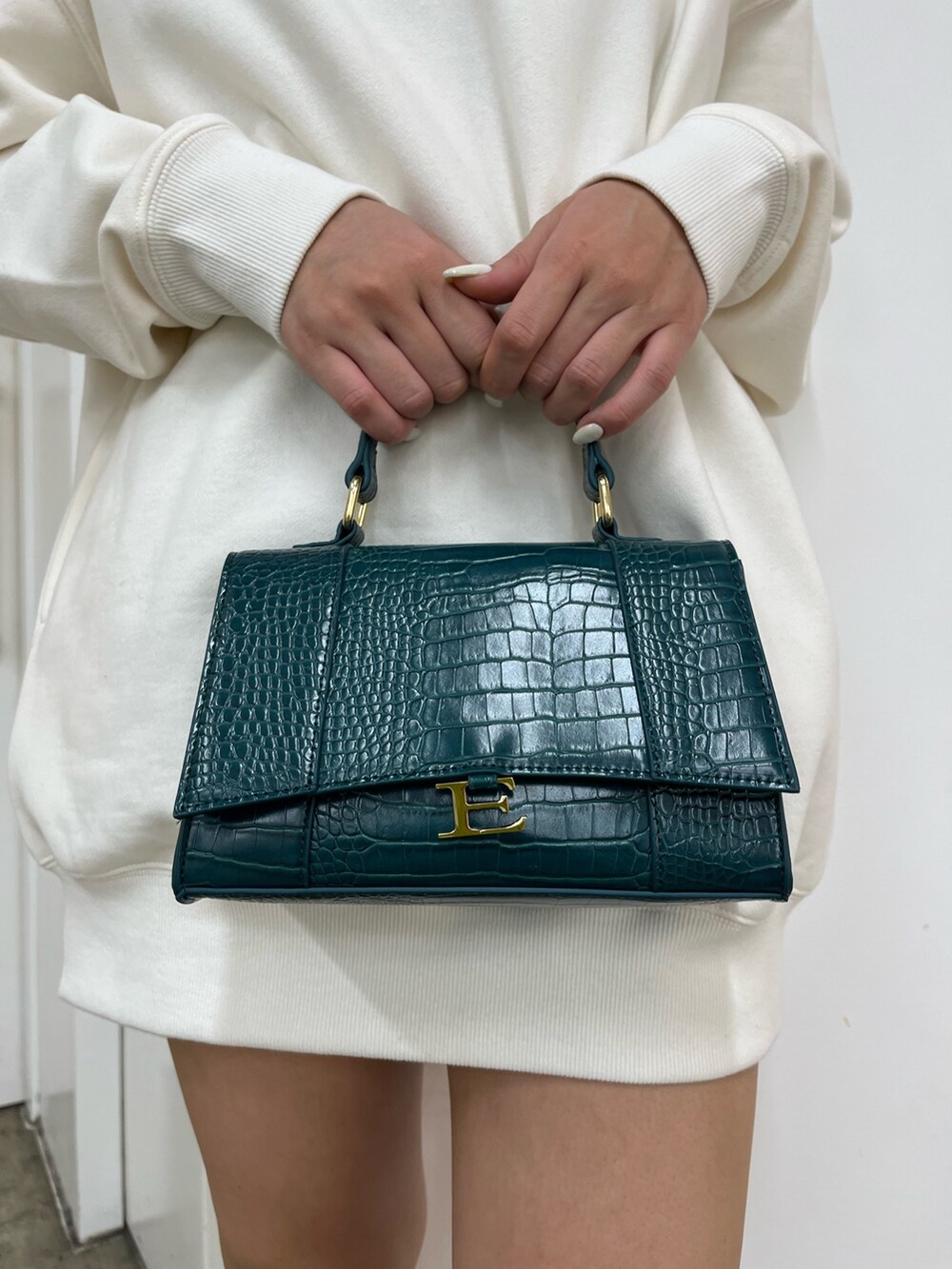 ホワイト系のスウェット、ブラック系のデニムスカート、ブラック系のブーツを着用したレディースの秋コーディネートの7枚目の写真