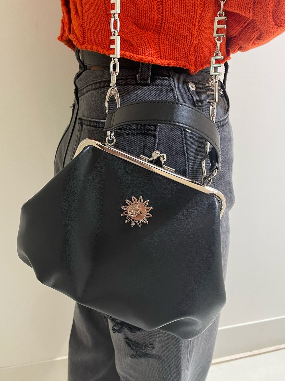 オレンジ系のカーディガン/ボレロ、ブラック系のデニムパンツ、ブラック系のショルダーバッグを着用したレディースの冬コーディネートの7枚目の写真