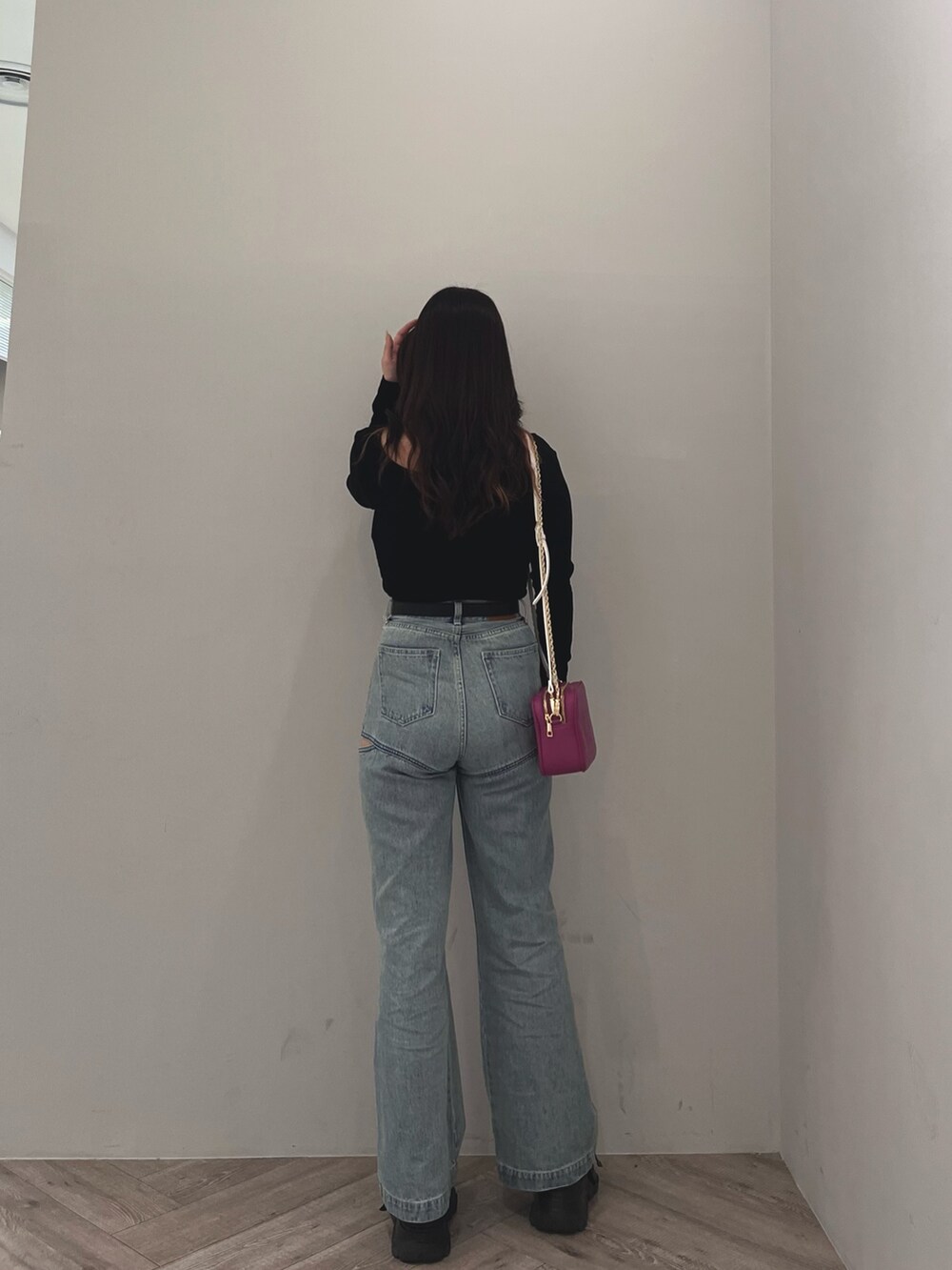 ブルー系のデニムパンツ、ブラック系のニット/セーター、パープル系のショルダーバッグを着用したレディースの春コーディネートの2枚目の写真