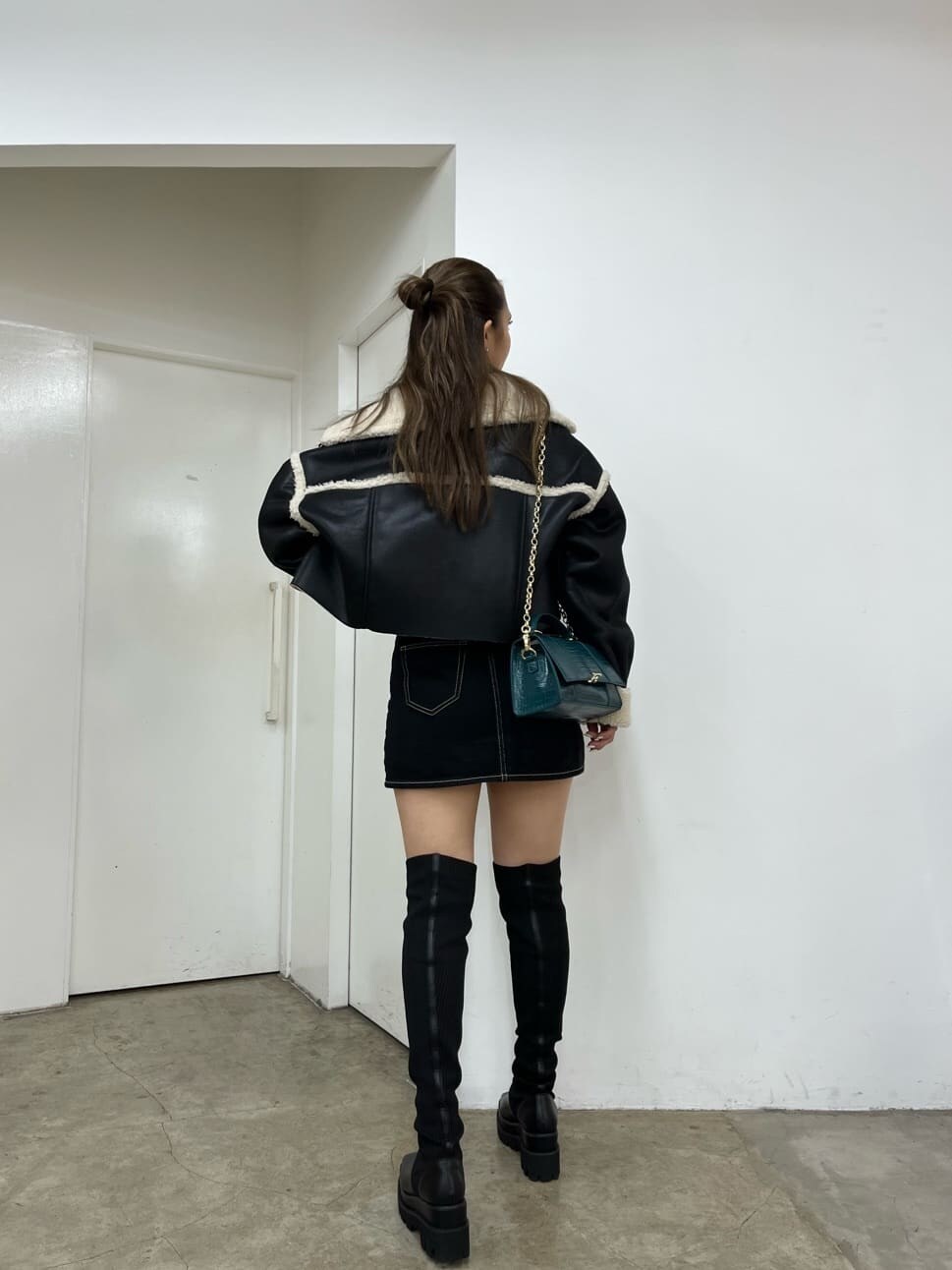 ブラック系のデニムスカート、ブラック系のブルゾン、ブラック系のブーツを着用したレディースの秋コーディネートの2枚目の写真