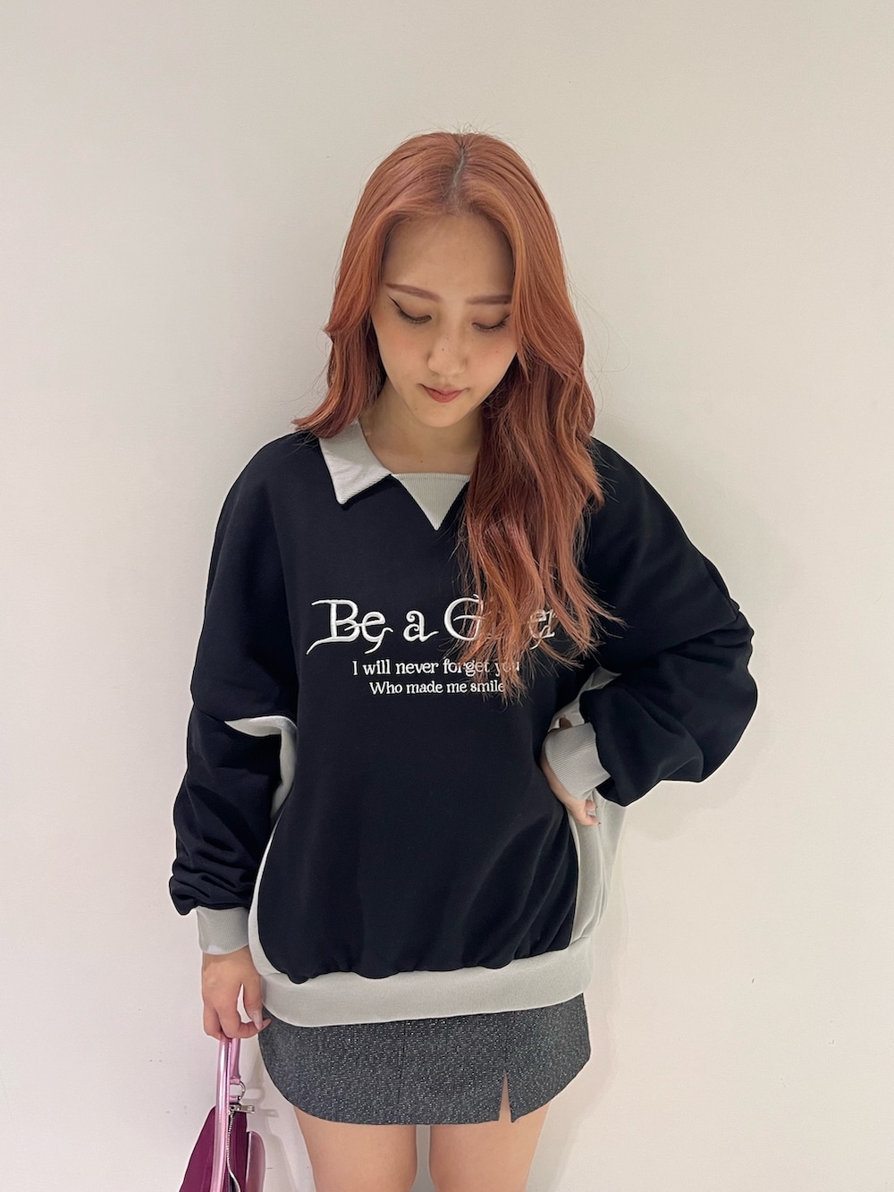 ブラック系のスウェット、グレー系のスカート、ピンク系のハンドバッグを着用したレディースの秋コーディネートの3枚目の写真