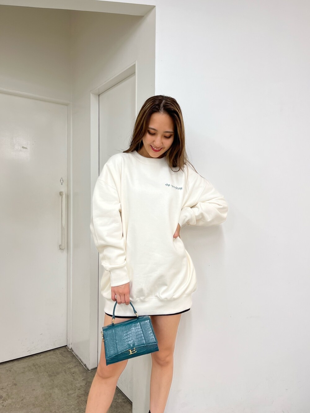 ホワイト系のスウェット、ブラック系のデニムスカート、ブラック系のブーツを着用したレディースの秋コーディネートの3枚目の写真