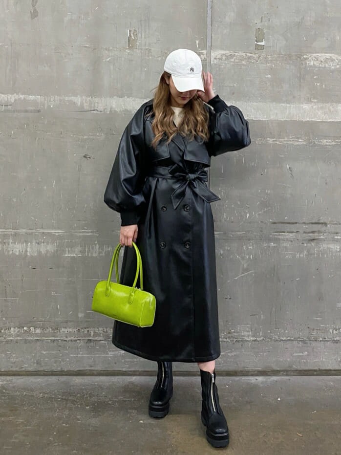 ブラック系のトレンチコート、グリーン系のボストンバッグ、ブラック系のブーツを着用したレディースの冬コーディネートの2枚目の写真