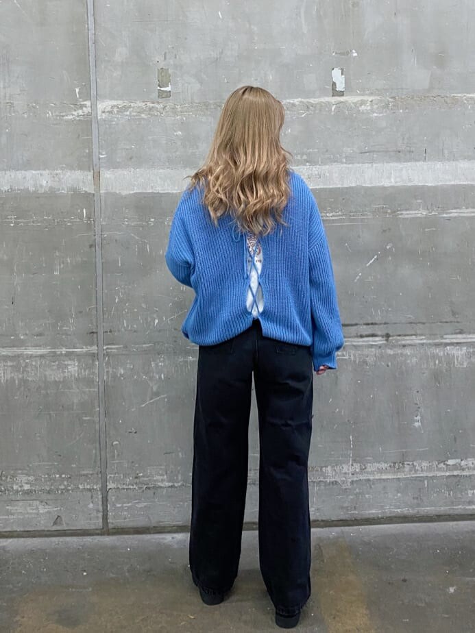 ブラック系のデニムパンツ、ブルー系のニット/セーター、ブラック系のブーツを着用したレディースの冬コーディネートの2枚目の写真
