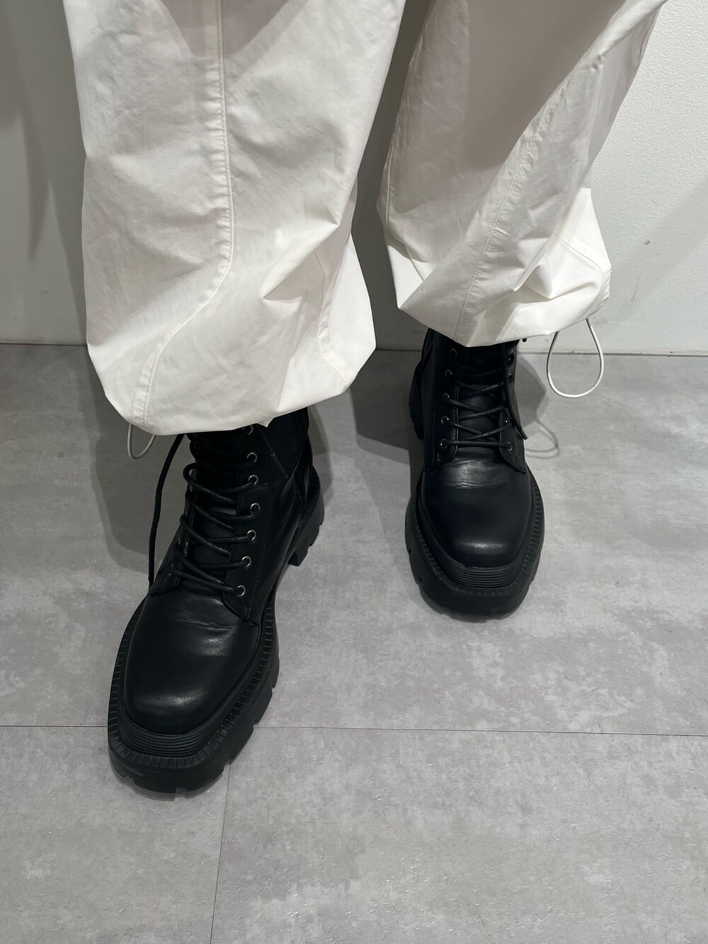 ブラック系のニット/セーター、ブラック系のブーツ、ホワイト系のカーゴパンツを着用したレディースの春コーディネートの6枚目の写真