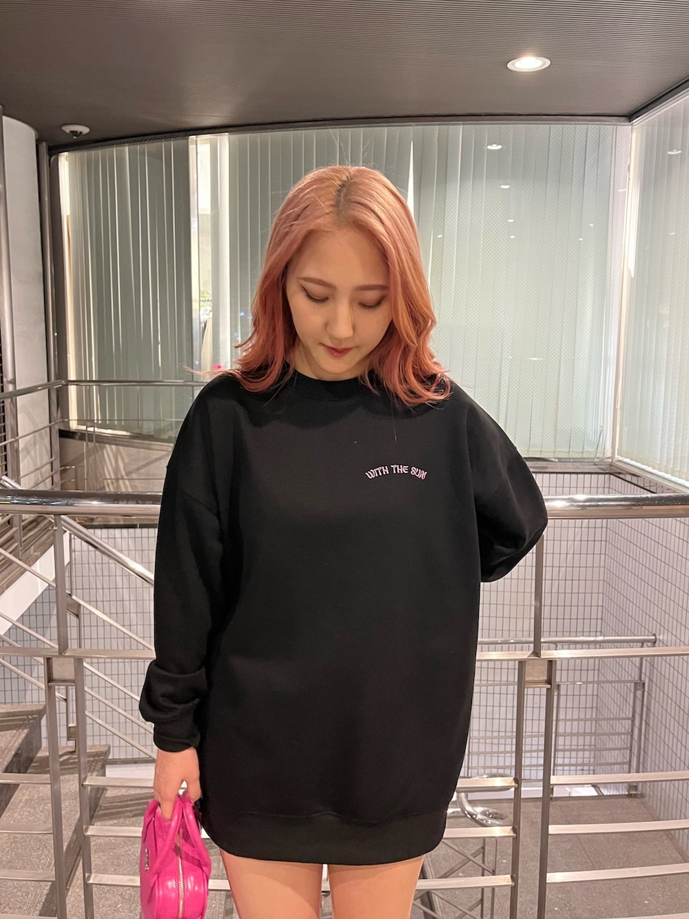 ブラック系のスウェット、ピンク系のショルダーバッグ、ブラック系のブーツを着用したレディースの冬コーディネートの5枚目の写真