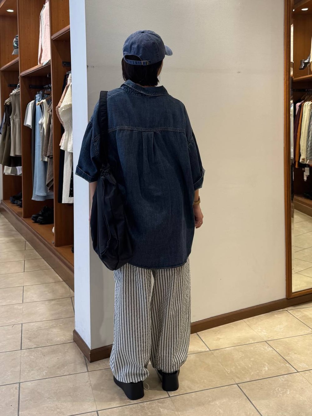 シルバー系のサンダル、ブルー系のシャツ/ブラウス、ブラック系のショルダーバッグを着用したレディースの春コーディネートの2枚目の写真